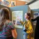 Female student explaining her research to another student in front of her poster