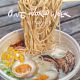 Bowl of Ramen noodles with chop sticks pulling noodles up and soft boiled egg cut in half