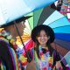 Attendees at Brighton Pride holding a rainbow umbrella