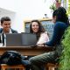 Three students chatting around a laptop