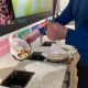 Diner's hands as they scrape food waste from their plate into the food waste bin, one of six recycling bins in Eat Central