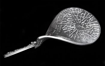 On a black background, a silver twisted key with an inscription celebrating the opening of the University Library