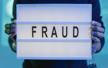 two hands holding a sign that reads 'fraud'