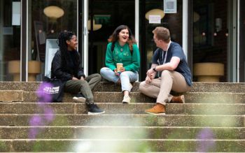 Three students chatting away on the stairs of the Meeting House