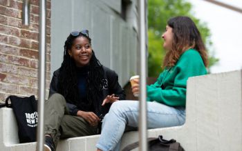 Two students chatting while having a coffee outside