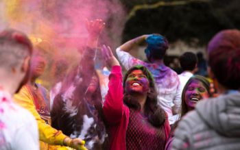 A photograph of students throwing coloured powders