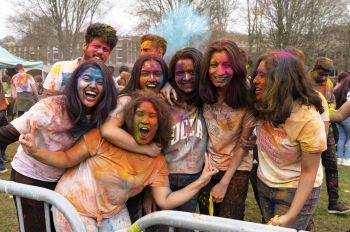 A group of students are covered in multi-coloured powder