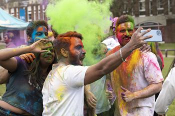 Students take selfies covered in coloured powder at the annual Holi celebration