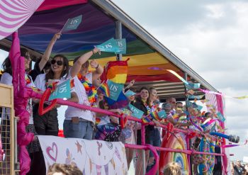 Students and staff waving from the University of Sussex pride float