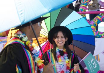 Attendees at Brighton Pride holding a rainbow umbrella