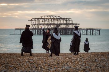 Graduands celebrating on the beach at Brighton in front of the ruined West Pier.