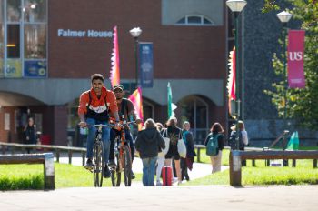 A young man rides his bike on campus