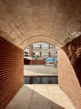 A photograph of Falmer House courtyard beyond a moat taken from within a brick arch.