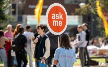 Student volunteer holding Ask Me sign during Welcome Week