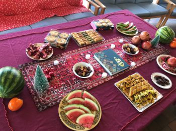 Iranian foods laid out on a table with a traditionally decorated table runner