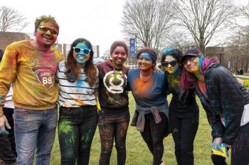 Students posing for a photo covered in coloured paint from the Holi festival