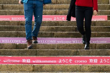 Students walking up steps that say 