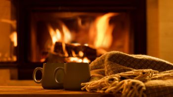 A cosy fire lit room with two hot chocolates steaming in mugs