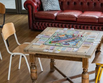 A monopoly board laid out on a table at the Northfield bar with a worn, comfortable looking sofa behind it