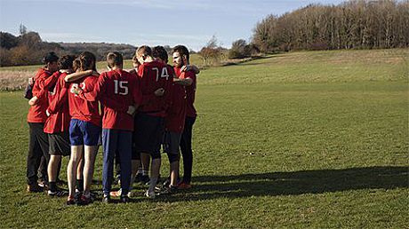 A group of sporting students huddle together on a sports field