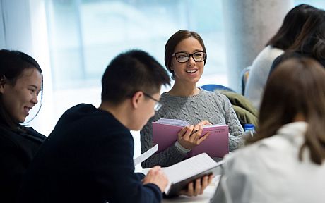 Postgraduate students in conversation holding notebooks