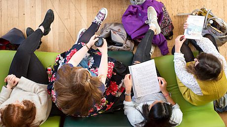 Students sitting on comfortable chairs in the common room, seen from above