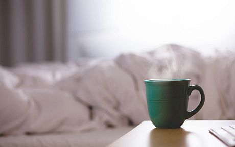 Green mug on table in front of white sheets