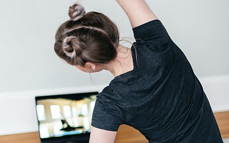 Woman doing yoga in front of laptop