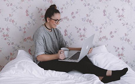 Young woman with laptop on bed