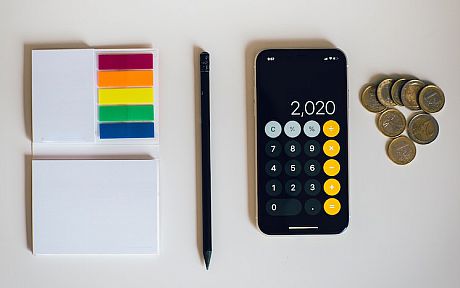 Calculator on phone next to pile of coins