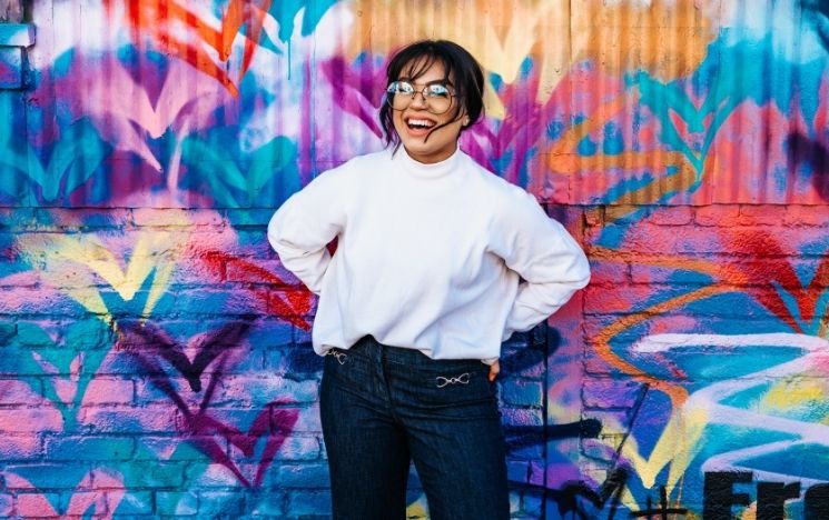 Young woman smiling in front of a graffiti