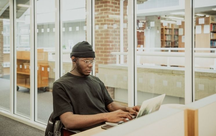 Black male student working on his laptop in the library