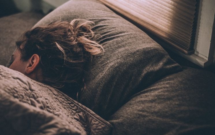 Woman sleeping on bed under a duvet