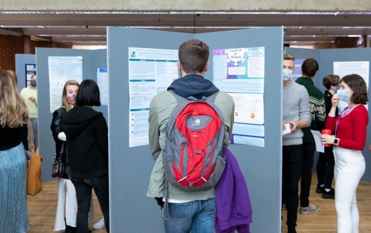 Student with a backpack observing a research poster
