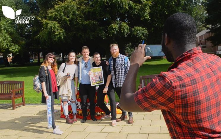 Student taking a photo of a group young people on campus