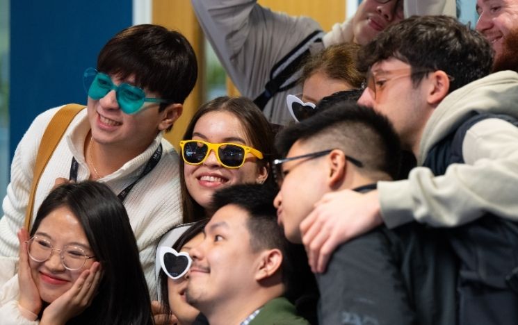  A group of students pose in a group smiling with different sunglasses on.
