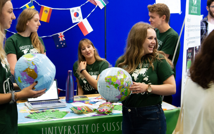 Students from Geogsoc holding inflatable globes at a stand