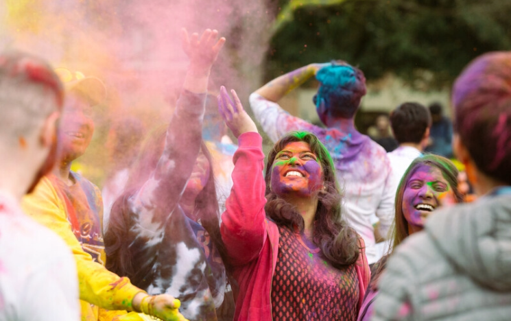 Students throw colourful paint powder in the air as part of Holi celebrations