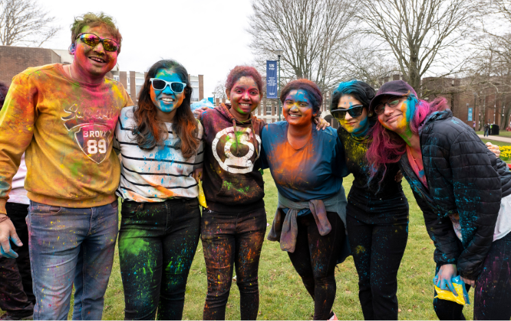 Students posing for a photo covered in coloured paint from Holi festival