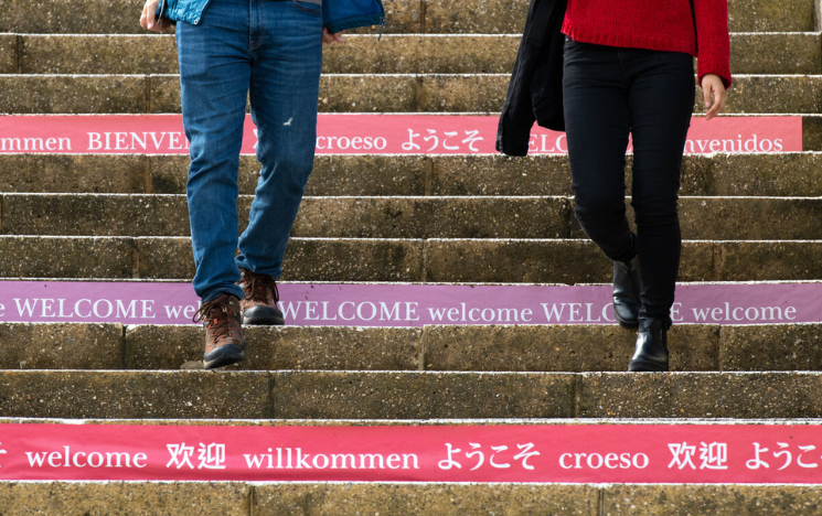 Students walking up steps that say 