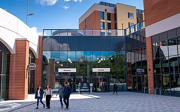 Four students walk away from the main entrance of the Student Centre on the Sussex campus in nice weather