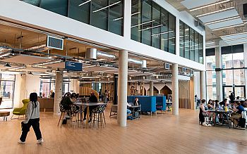 Students working inside the main foyer of the Student Centre, with the Welcome desk in the background