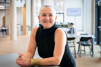 Professor Kate O’Riordan sat at a table, smiling to camera.