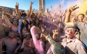 Crowd covered in colours smiling at the camera during Holi 2017