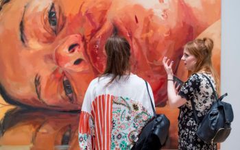Two women appreciating a large painting in one of the exhibitions