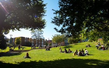 Photograph of students sat out on the grass on campus